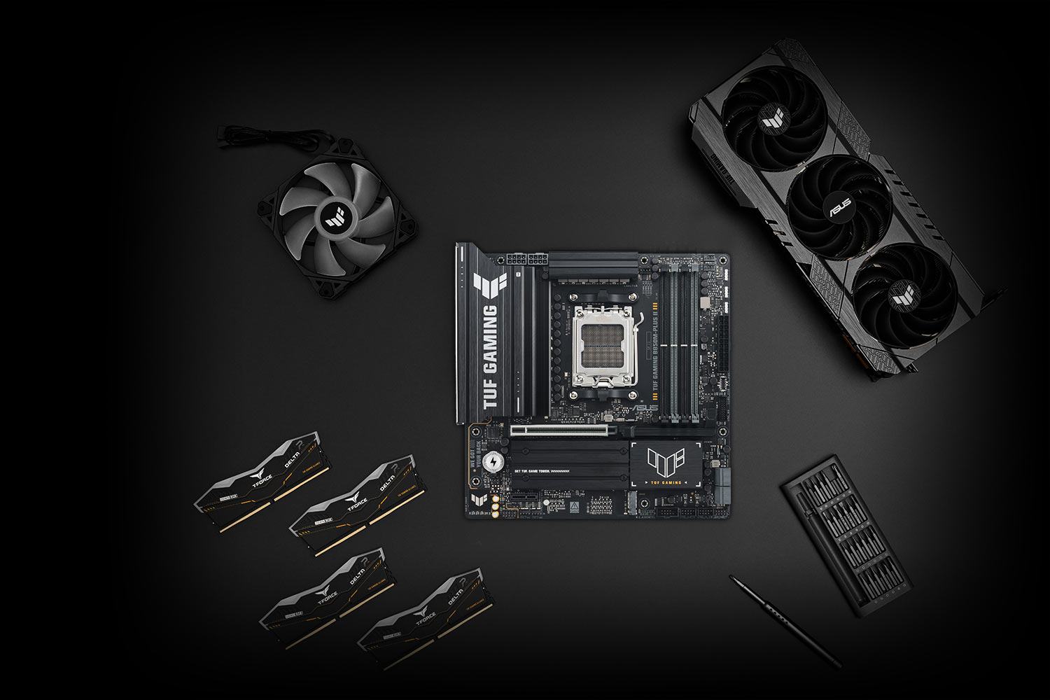TUF GAMING B850M-PLUS II 主板放置在金属表面上，周围整齐地摆放着各种兼容的 PC 组件，包括 M.2 固态硬盘和内存，代表着 TUF GAMING 联盟，以确保构建的兼容性。