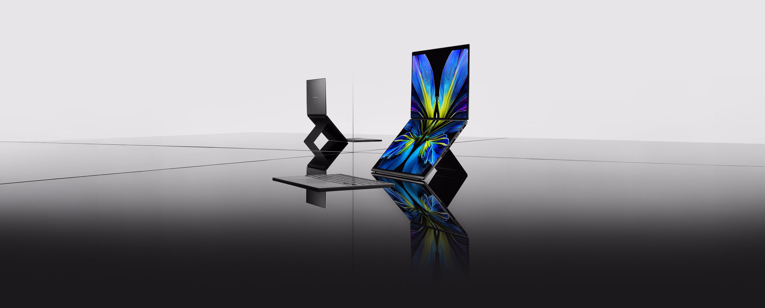 Two ASUS灵耀双屏are displayed in a minimalist, reflective setting.