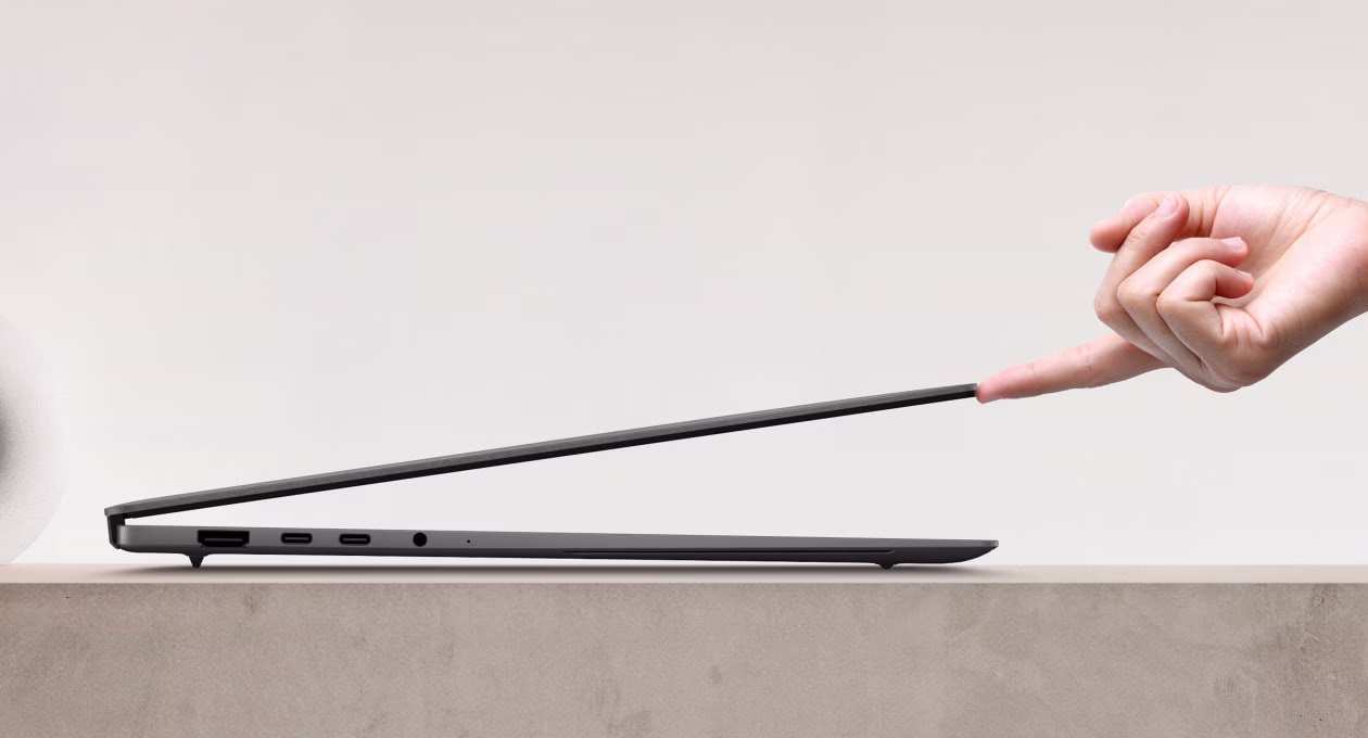 A single finger effortlessly lifts a sleek laptop, showcasing its smooth hinge and minimalist design.