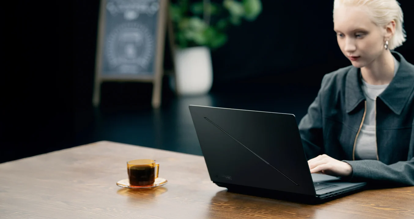 a woman using 幻16 双屏with the laptop mode in a coffee shop.