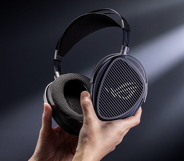 Hands holding the ROG臻世headset, showing the open-back earcup design and ROG grille aesthetics