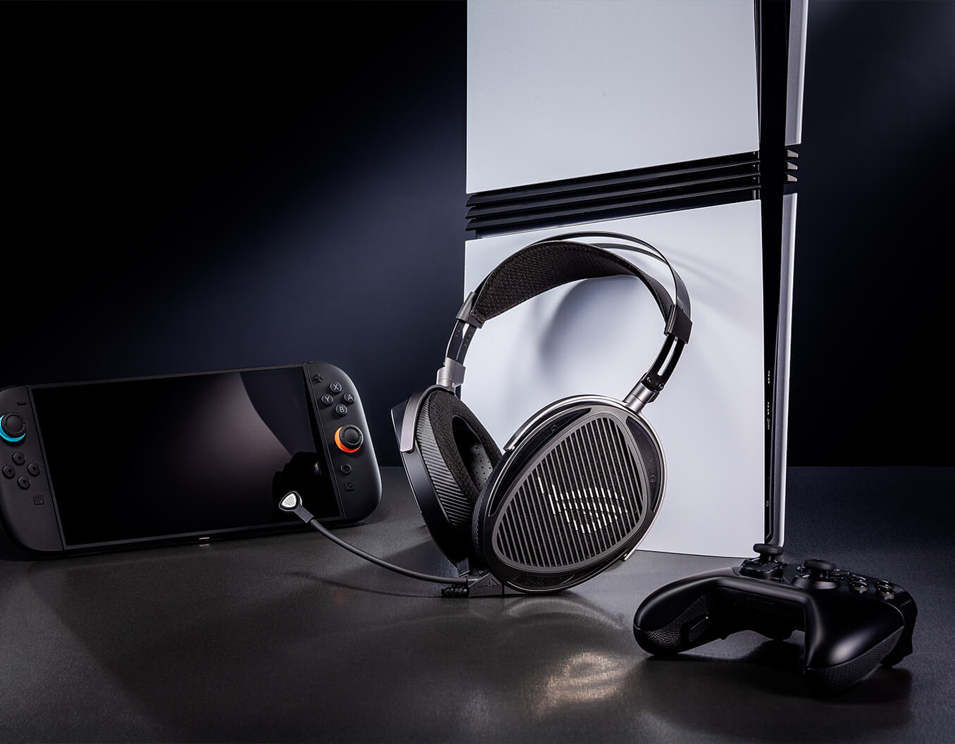 ROG臻世headset placed next to a game console, a wireless game controller, and a handheld gaming device on a dark surface.