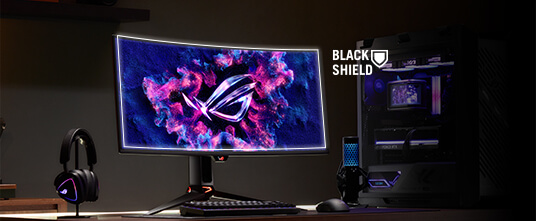 ROG PG34WCDN 曲面电竞显示器，屏幕上亮起 ROG Logo。图中展示了包含耳机、键盘、鼠标和电脑主机的全套桌面场景。右侧显示的 BlackShield 图标，示意该面板拥有更高的硬度与更佳的抗刮擦性能。