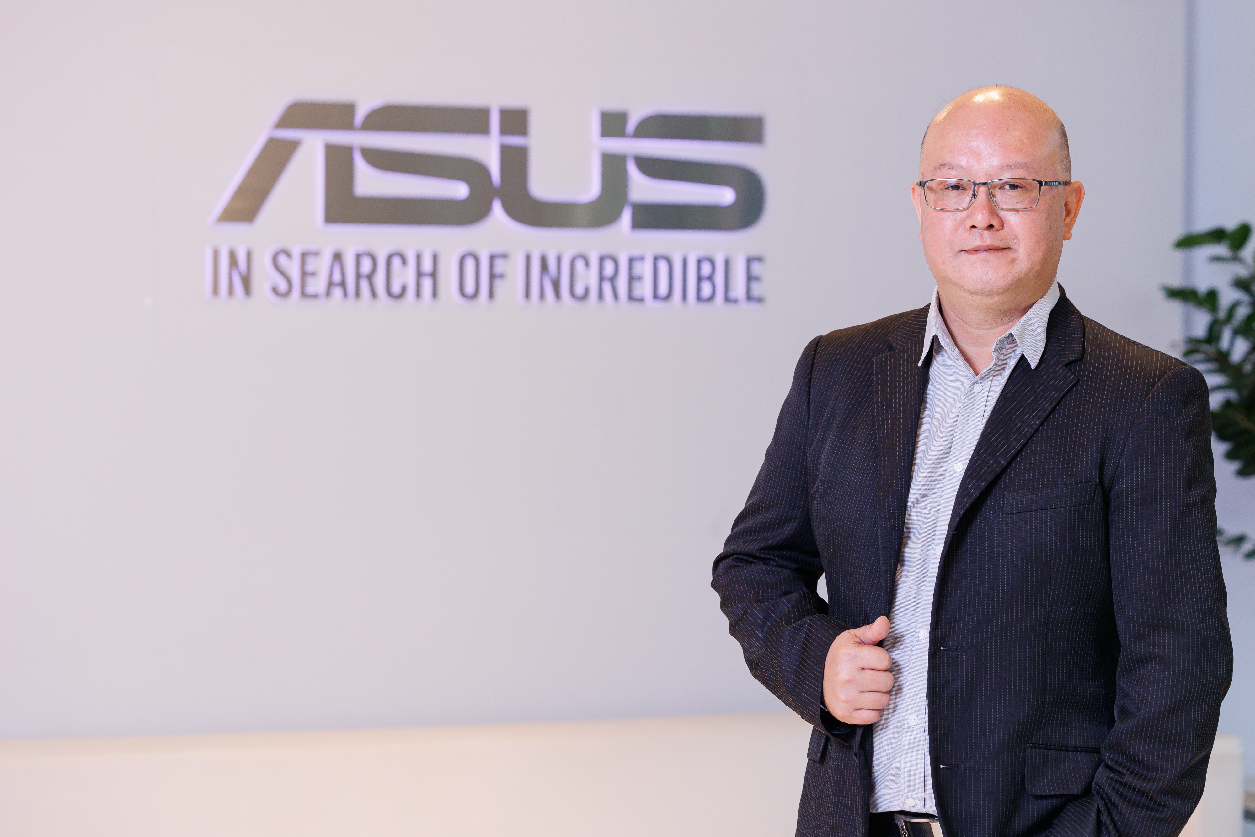 Clark Chang, Sales Manager at ASUS, standing confidently in front of the ASUS logo and the “In Search of Incredible” slogan, conveying a professional corporate setting.