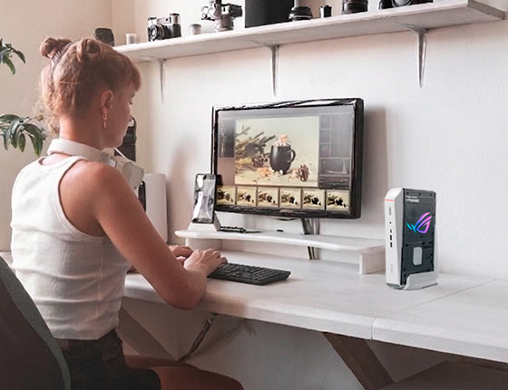 一名女孩正在使用 ROG NUC 16 一边喝咖啡一边修图