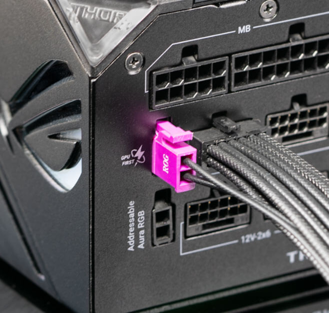 Close-up view of a power supply unit's modular interface showing a 12V2x6 connector with a purple latch and black sleeved cables plugged into the port.