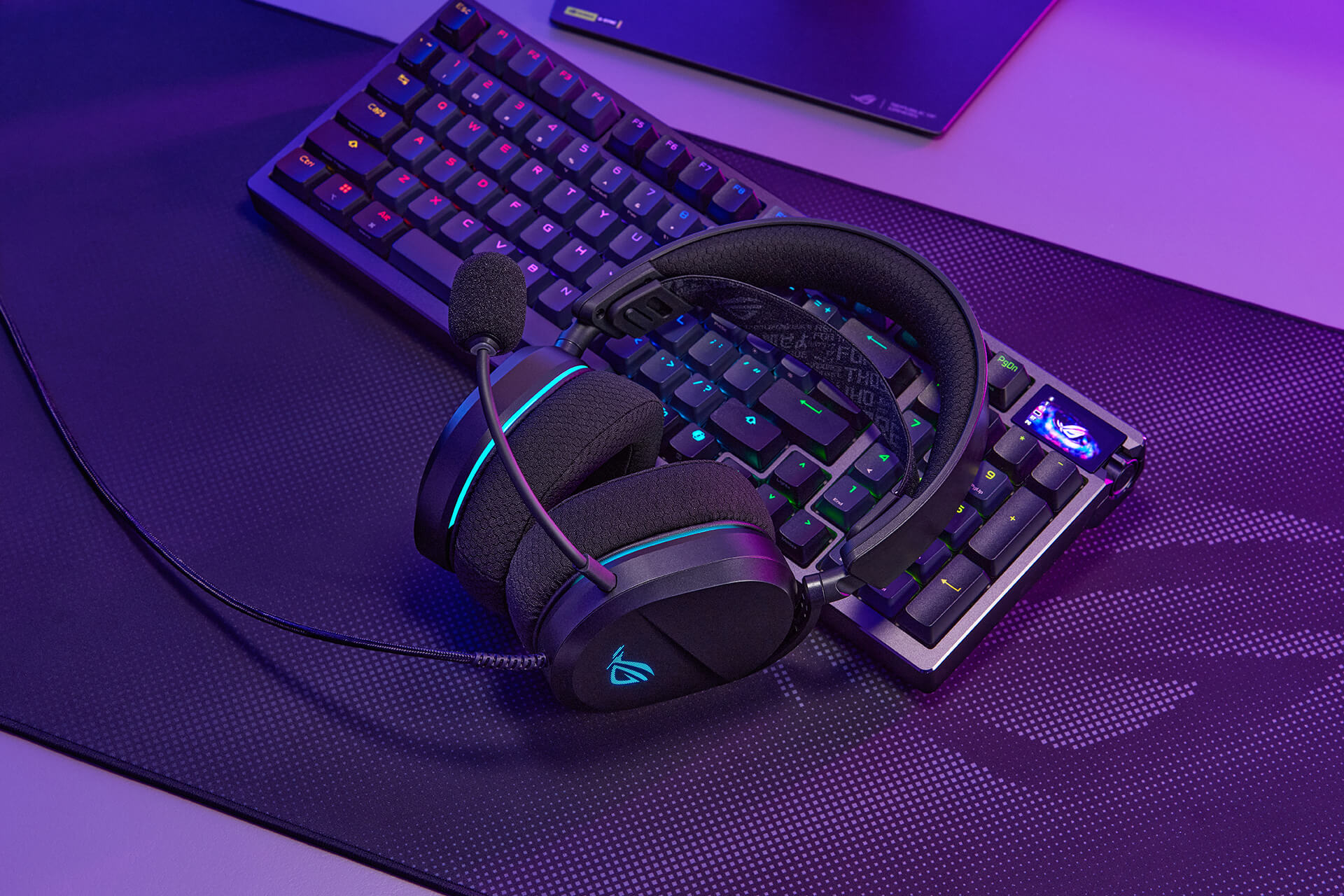 ROG 破风 标准版gaming headset resting on a keyboard and a mousepad.
