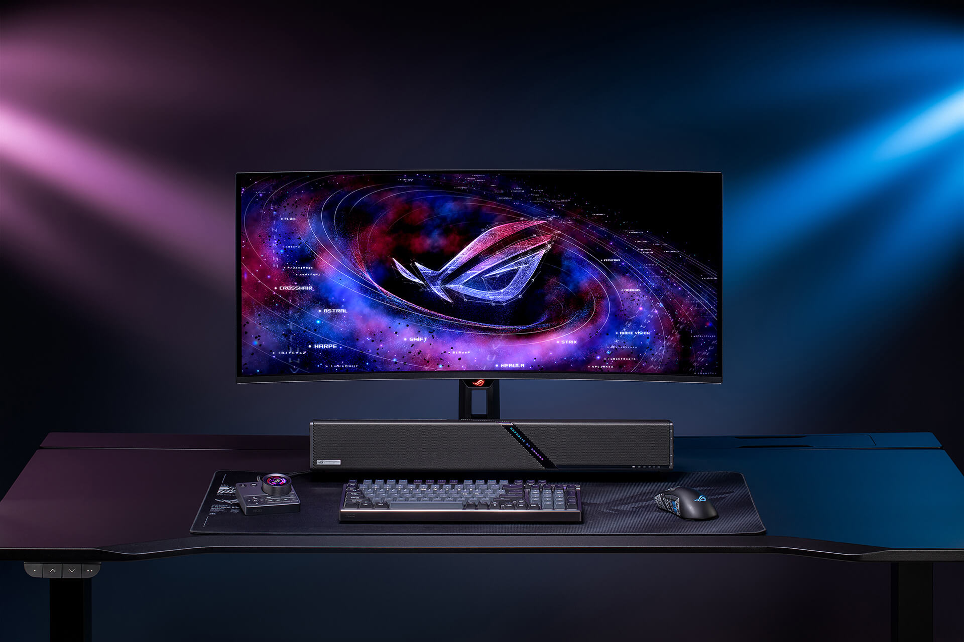 A sleek gaming setup on a black desk featuring a curved ultrawide monitor. Below the screen sits a ROG 加拉尔soundbar, a keyboard, and a mouseresting on a mousepad.