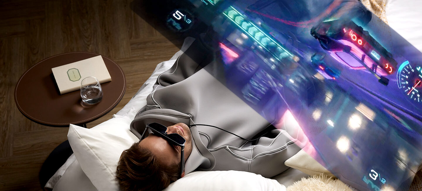 玩家躺在床上配合 R1 20周年版和 ROG Xbox Ally 掌机享受沉浸式游戏体验