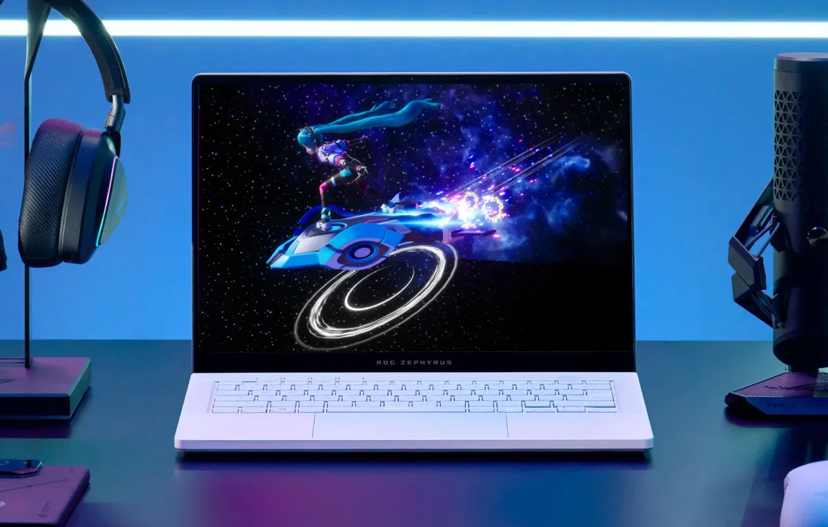 A white ROG laptop on a desk with a mic and headset, and a racing game on screen.