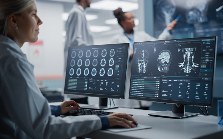 在一家医学研究中心，一名女医生正在通过两台电脑显示器查看病人的脑部超声波图像。