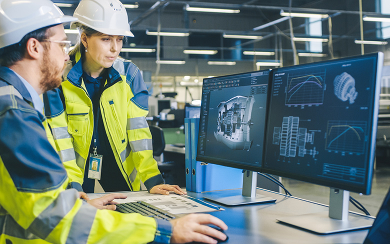 两名工程师在电脑前查看工程制造图纸。