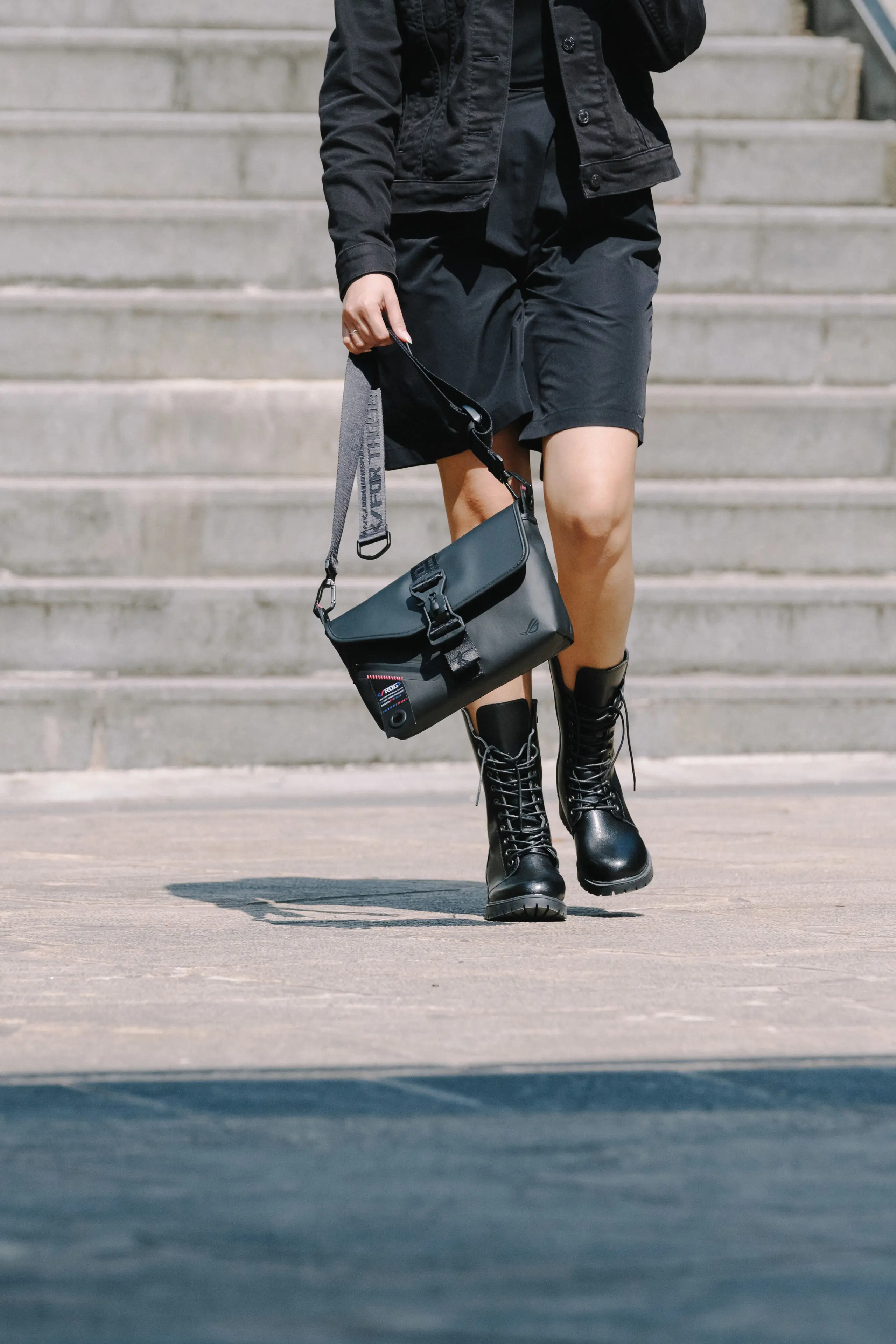 Close-up shot of a person walking on concrete with the ROG SLASH Sling Bag 2.0 held in their hands