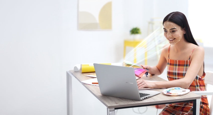 多束光束投射到女性的脸上，表明她的面部正在被笔记本电脑红外摄像头扫描。