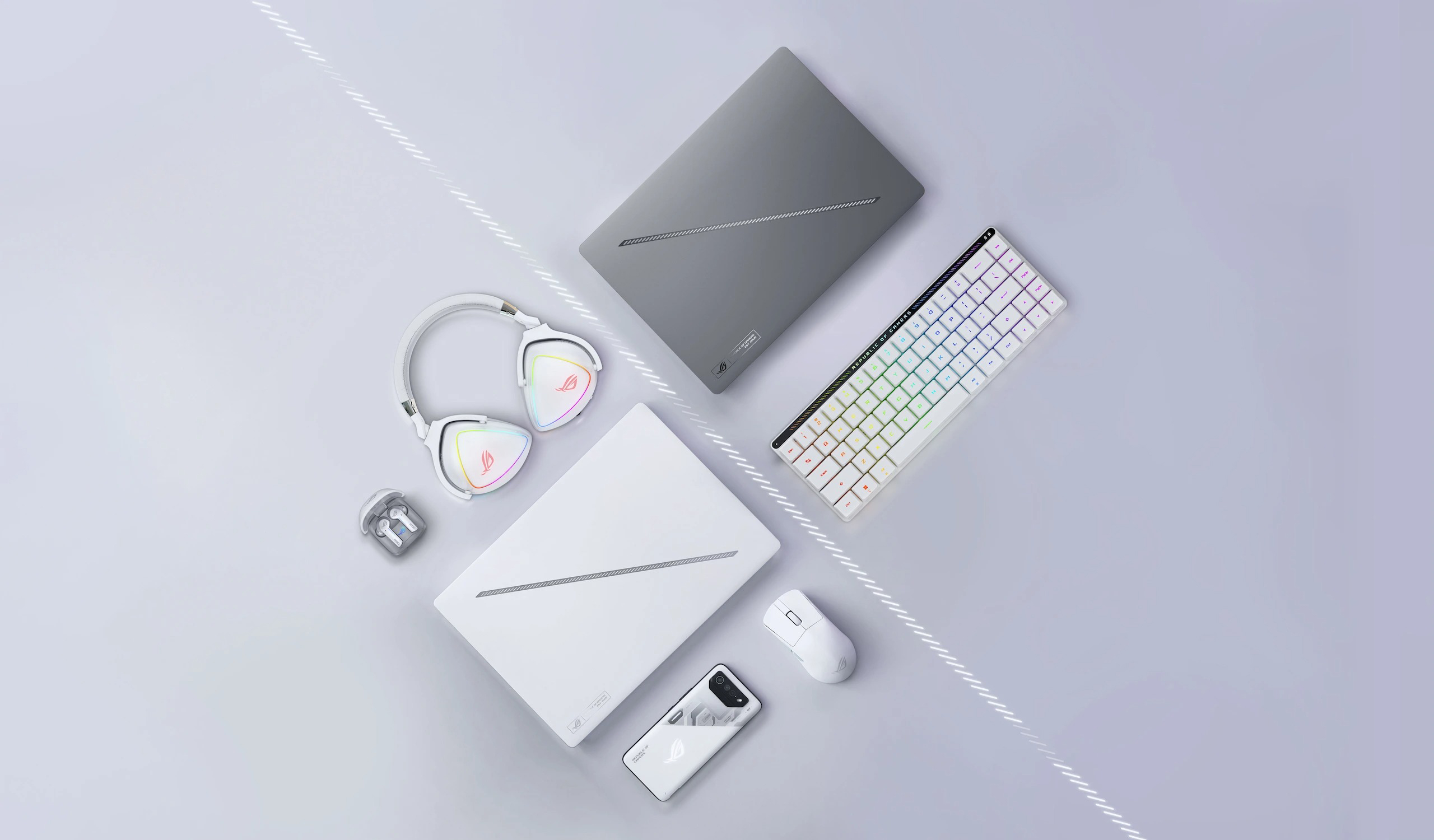 A top-down view of the Zephyrus G14, in Eclipse Grey and Moonlight White, divided by a line. Arranged near the laptops are headphones, a phone, a mouse, and a wireless keyboard.
