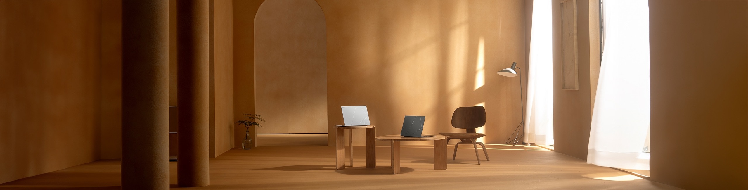 Two Zenbooks are placed on two wooden tables with spacious surroundings.