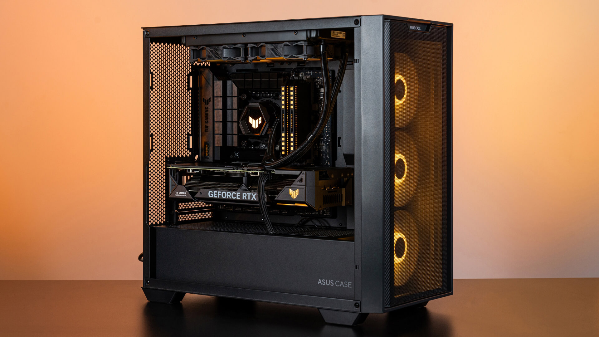 BTF 组装计算机(Powered By ASUS / PBA) 45 度角画面，呈现橘色灯效，并展示组装计算机中的 VGA 电源线。
