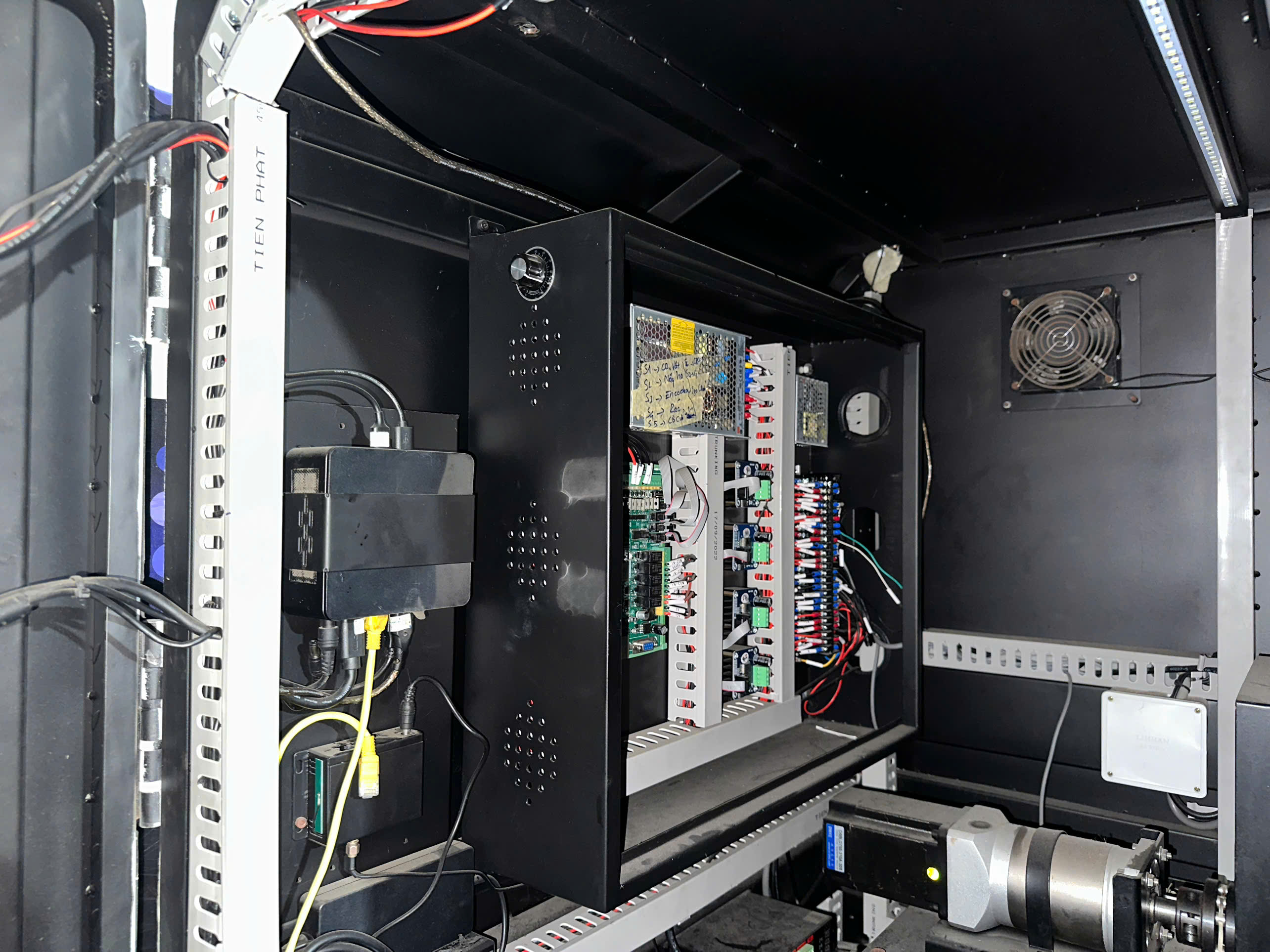A black cabinet filled with various wires and electronic components, showcasing a complex internal setup.