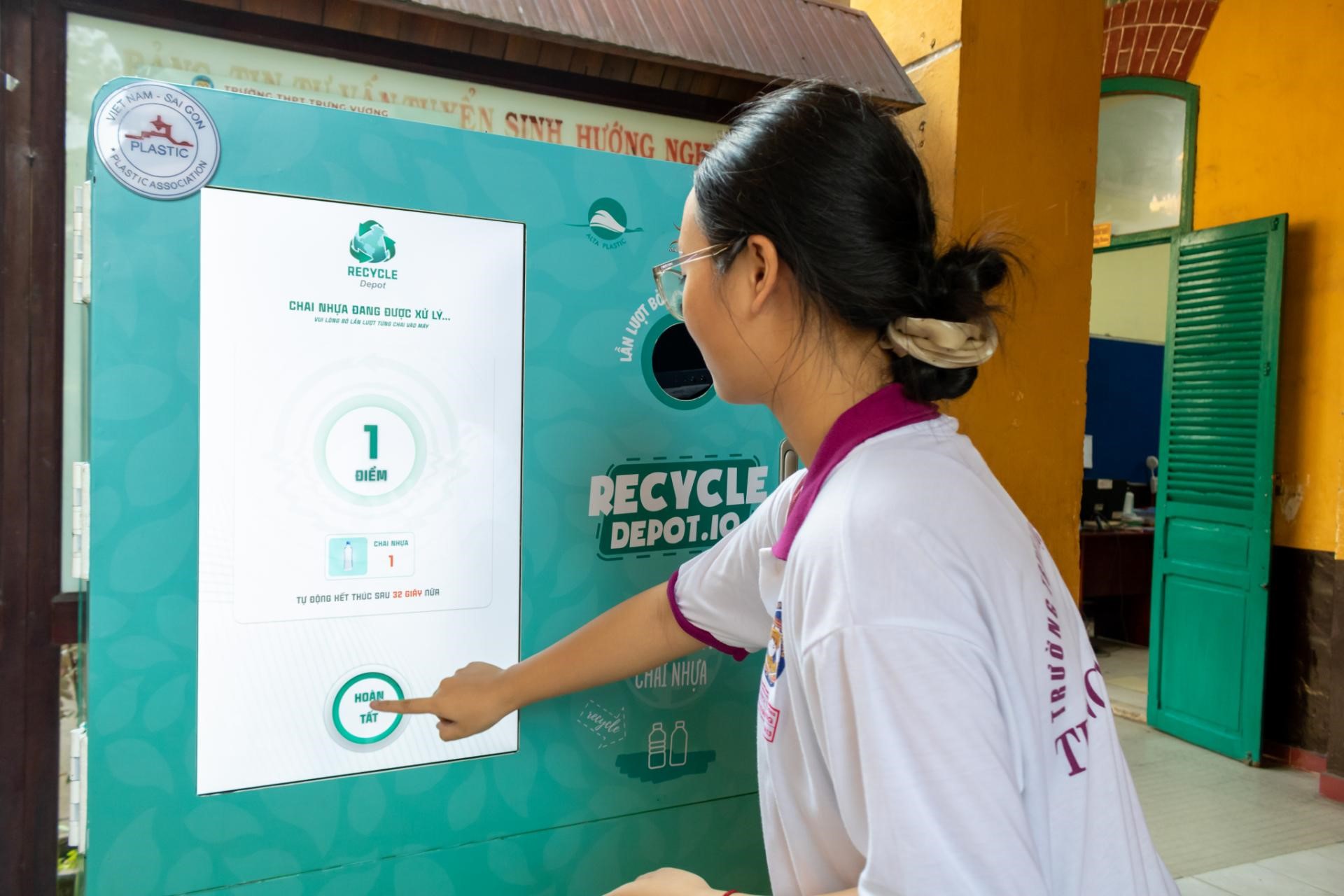 A woman in a white shirt operates a recycling machine, actively participating in waste management and sustainability efforts