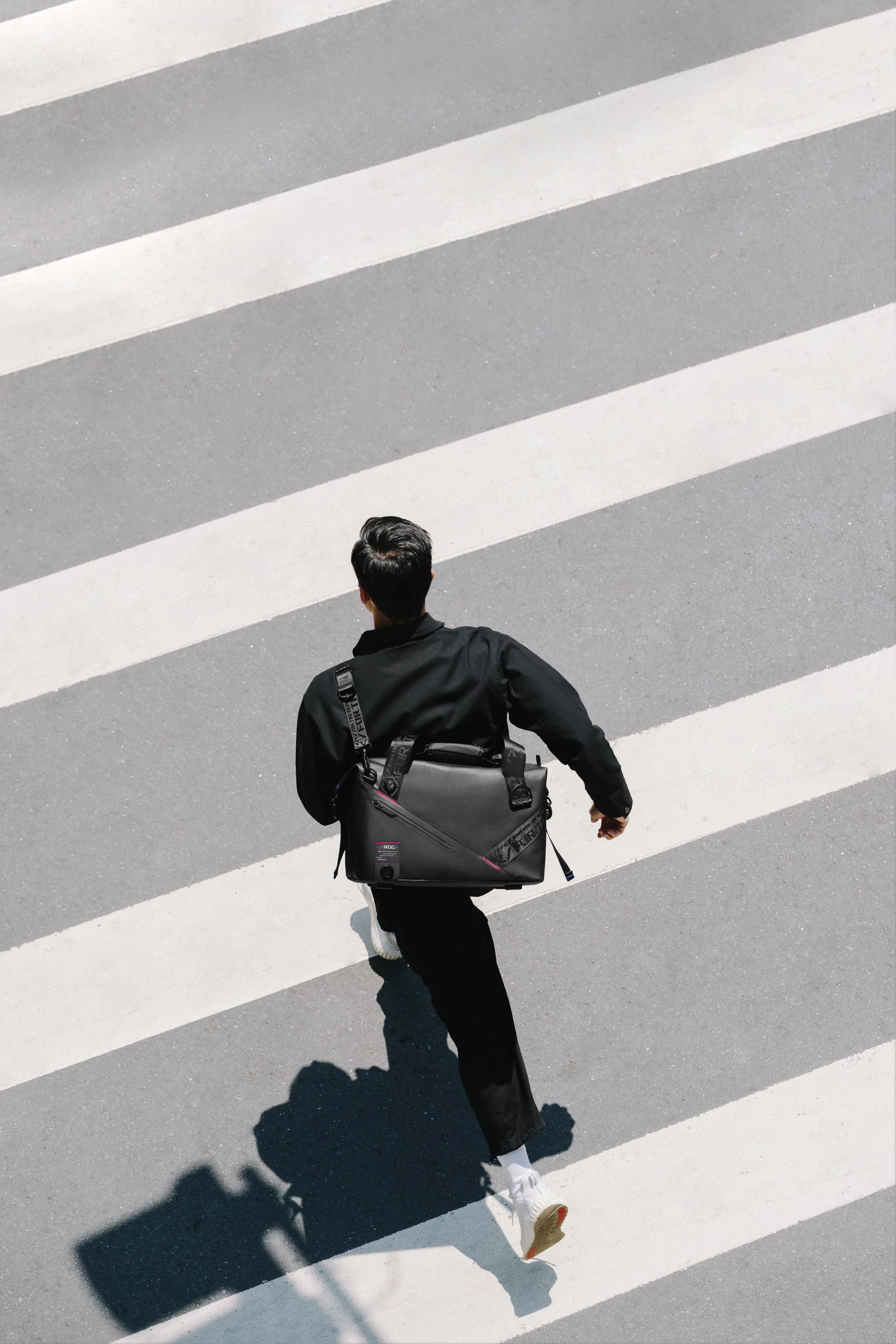 Image of a person running across a sidewalk with the ROG SLASH Duffle Bag over their shoulder