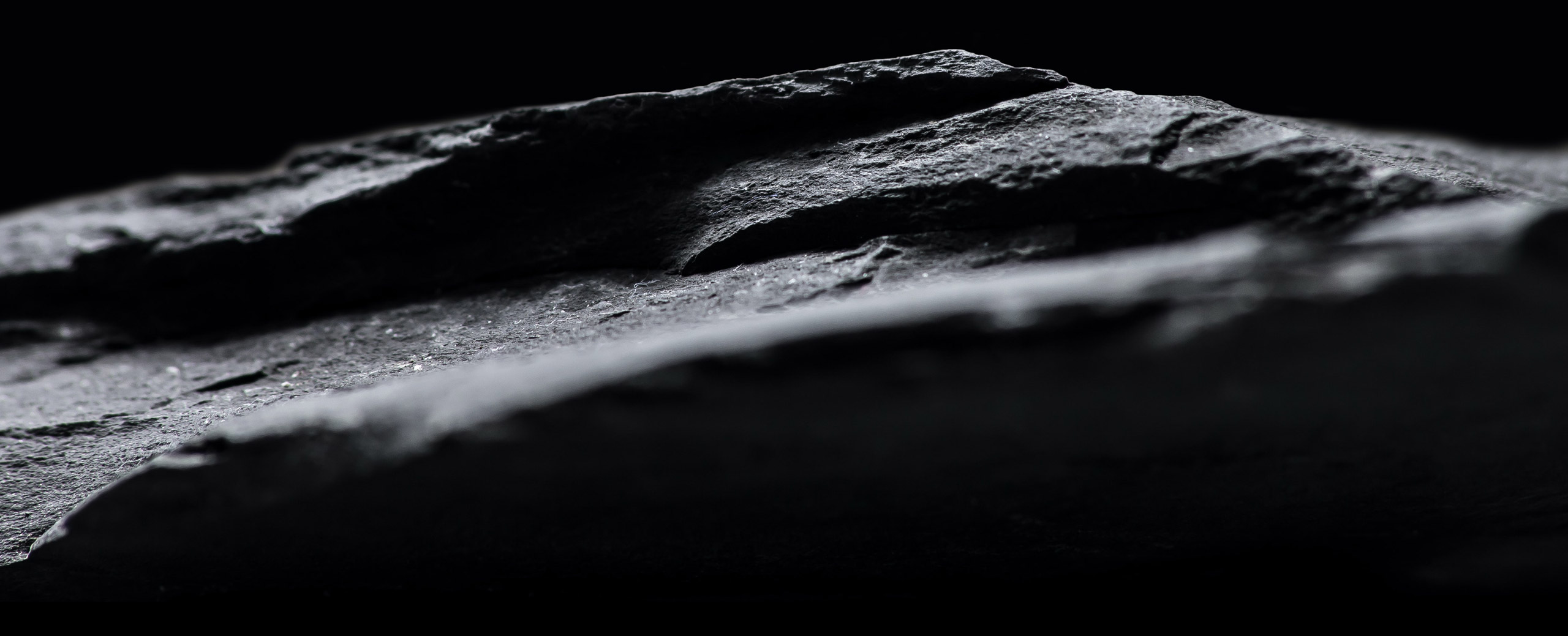 Moonlight White and Eclipse Gray circles, overlapping each other with a dark relief of a rock in the background. Slowly two laptops rise from the bottom of the screen to cover the two colored circles, then a tile explaining the Prismatic Film completely covers the page. 