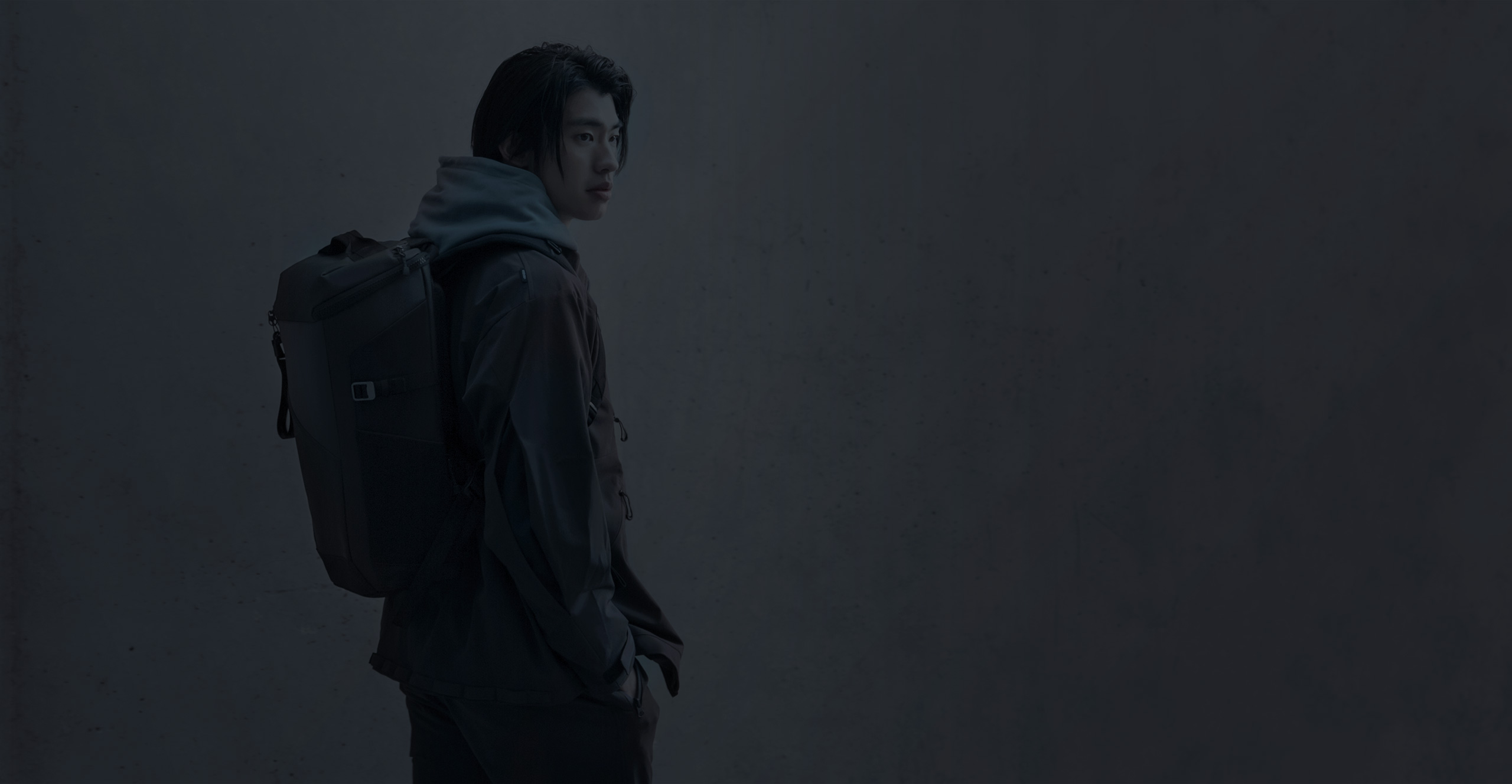 A rear view of a person wearing the ROG Ranger BP2701 Gaming Backpack and looking over their shoulder. 